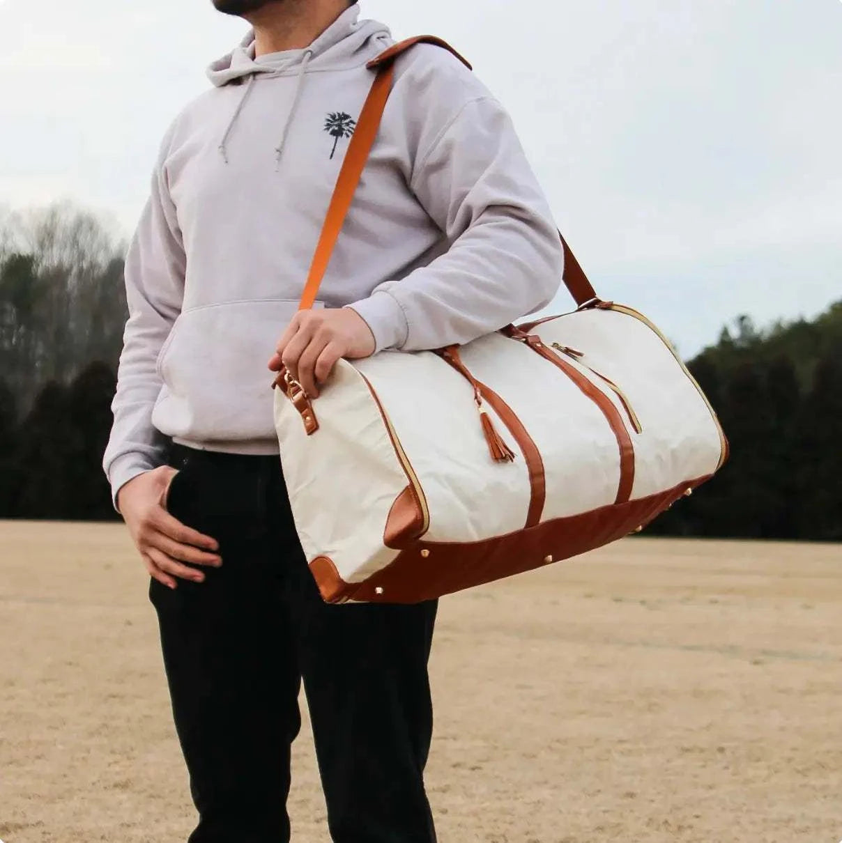 Man carrying a stylish Voyager Travel Bag with leather straps.