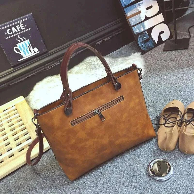 Wax oil leather bag with double handles and front zipper pocket, displayed in a cozy setting with shoes and a plush rug.