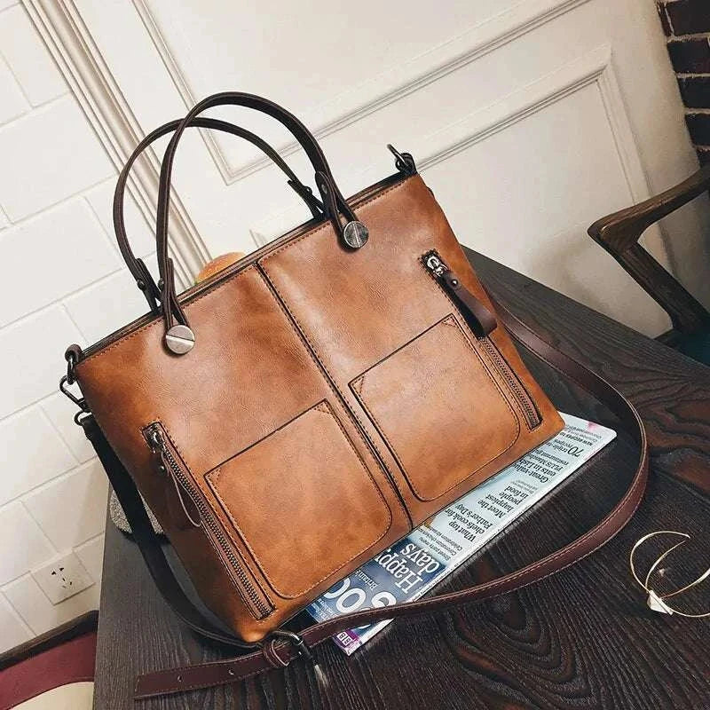 Wax Oil Leather Bag on a table, handcrafted with brown leather, dual handles, and exterior pockets.